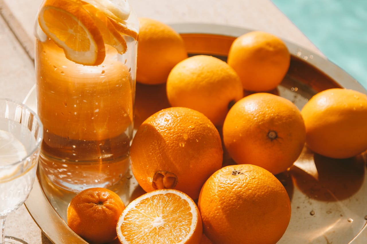Bright and fresh citrus fruits with a glass pitcher of orange juice on a sunny tray setting.
